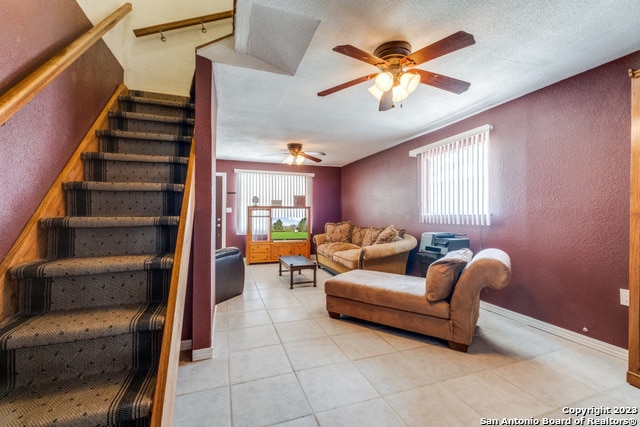 tiled living room featuring ceiling fan and a textured ceiling