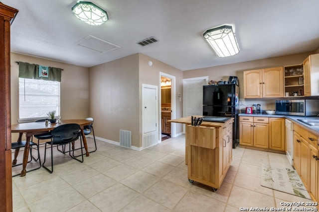 kitchen featuring light tile floors, a center island, black refrigerator, dishwasher, and sink