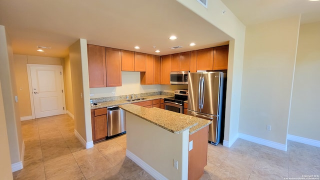 kitchen featuring sink, light tile patterned floors, a kitchen island, light stone counters, and stainless steel appliances