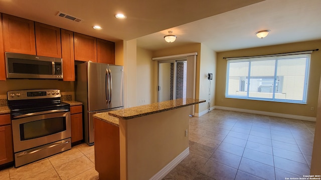 kitchen with light stone countertops, a center island, stainless steel appliances, and light tile patterned flooring