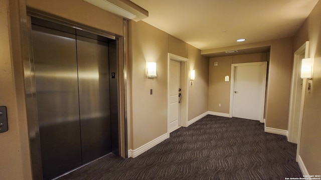 hall with elevator and dark carpet