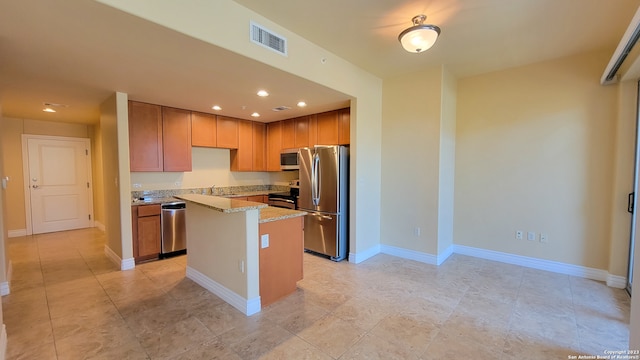 kitchen featuring appliances with stainless steel finishes, a center island, and light stone counters