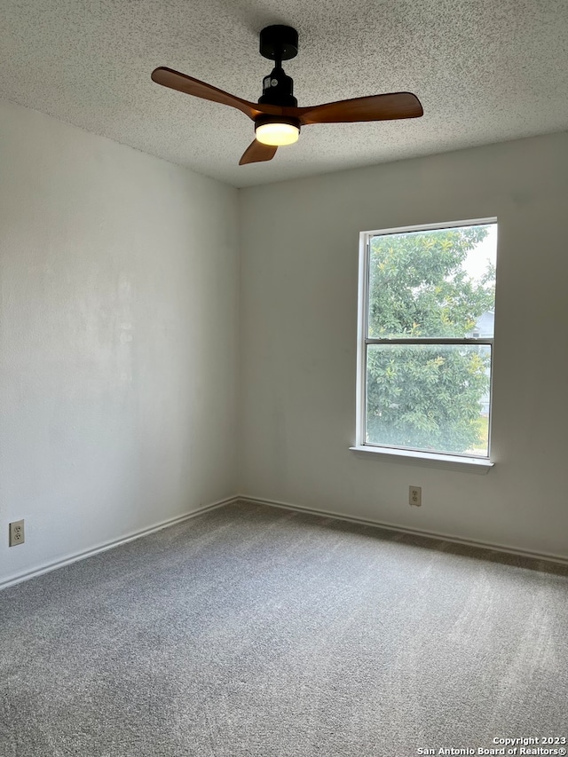 empty room with plenty of natural light, carpet flooring, and ceiling fan