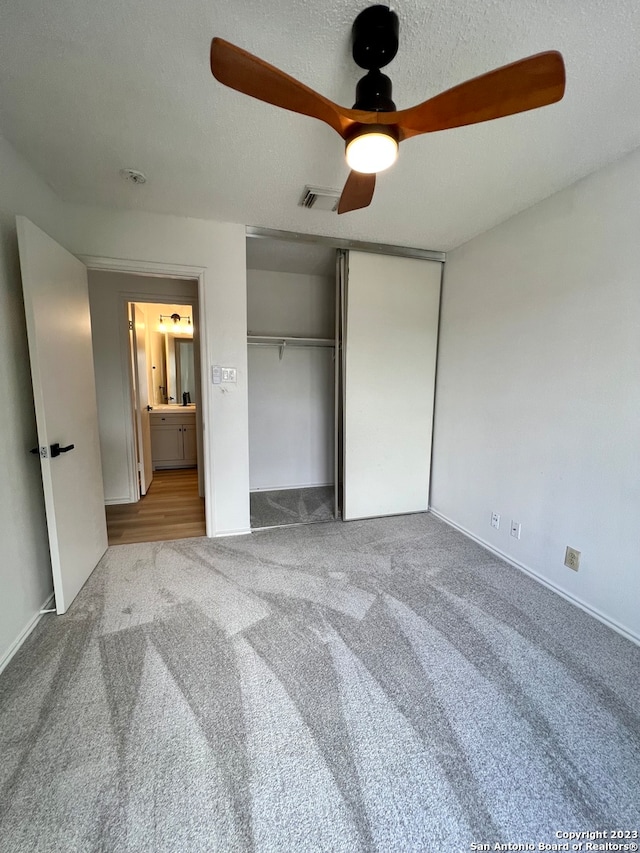 unfurnished bedroom featuring a textured ceiling, light colored carpet, and ceiling fan