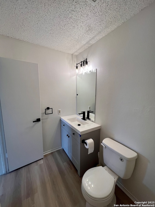 bathroom with toilet, a textured ceiling, vanity, and hardwood / wood-style flooring