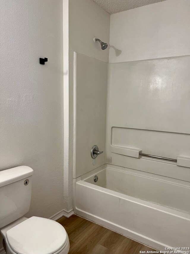 bathroom with  shower combination, toilet, a textured ceiling, and wood-type flooring