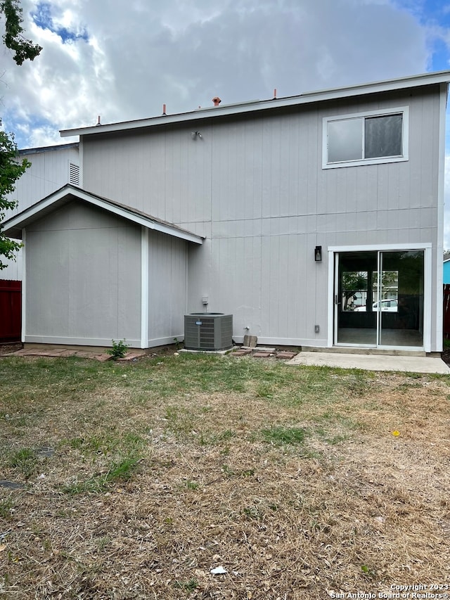 rear view of house with central AC unit and a yard