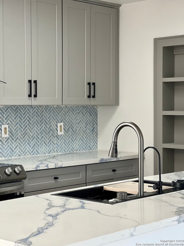 kitchen featuring light stone countertops, gray cabinetry, backsplash, and stainless steel electric stove