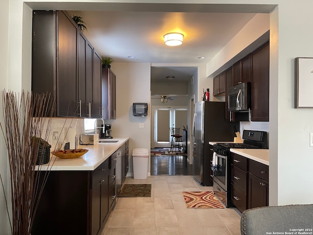 kitchen featuring stainless steel appliances, ceiling fan, tasteful backsplash, dark brown cabinets, and sink