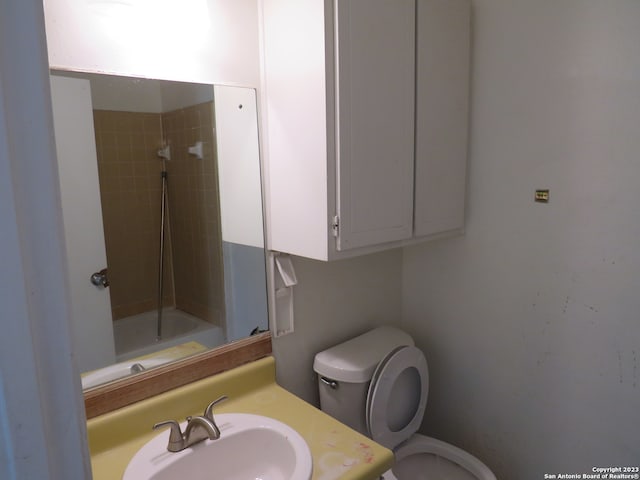 full bathroom featuring tiled shower / bath combo, toilet, and sink