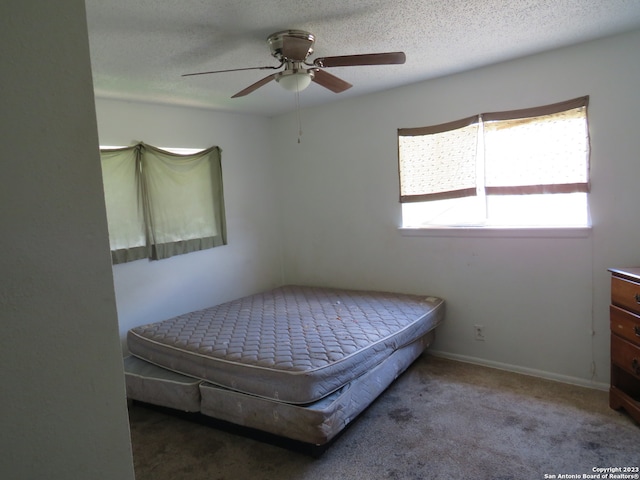 bedroom featuring dark colored carpet, ceiling fan, and a textured ceiling