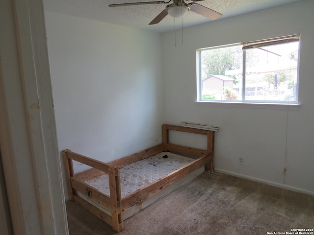 unfurnished bedroom featuring carpet flooring, ceiling fan, and a textured ceiling