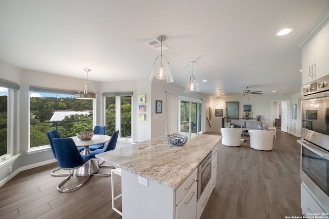 kitchen with white cabinetry, dark wood-type flooring, ceiling fan, a center island, and plenty of natural light