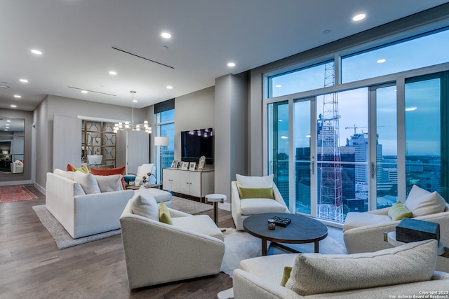 living room with light hardwood / wood-style floors, a wall of windows, and a chandelier