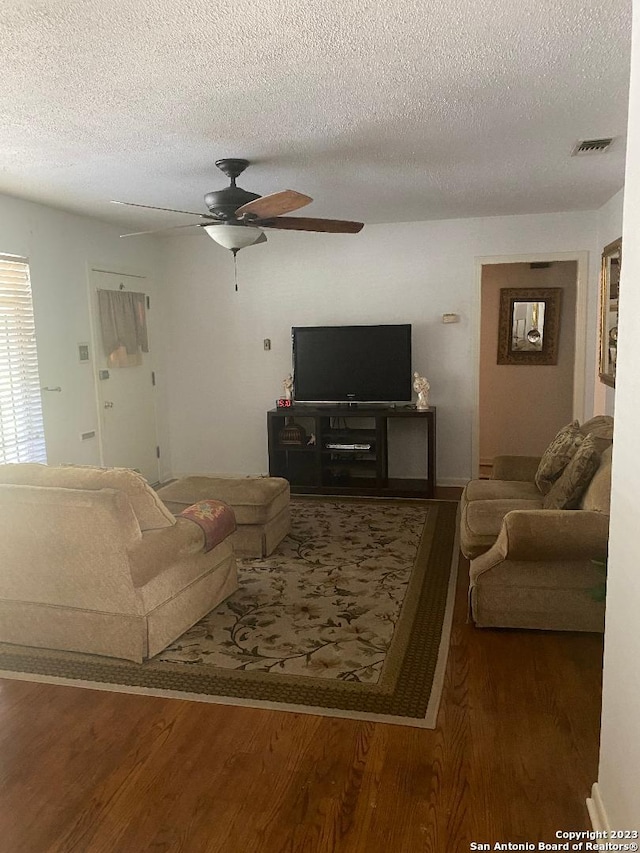 living room with ceiling fan, a textured ceiling, and dark hardwood / wood-style flooring