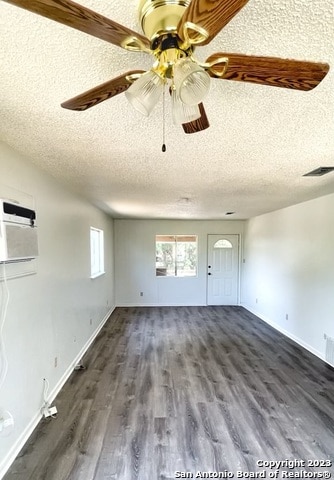 empty room featuring ceiling fan, a textured ceiling, and dark wood-type flooring