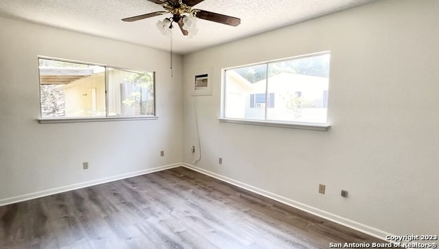empty room with ceiling fan, a textured ceiling, and dark wood-type flooring
