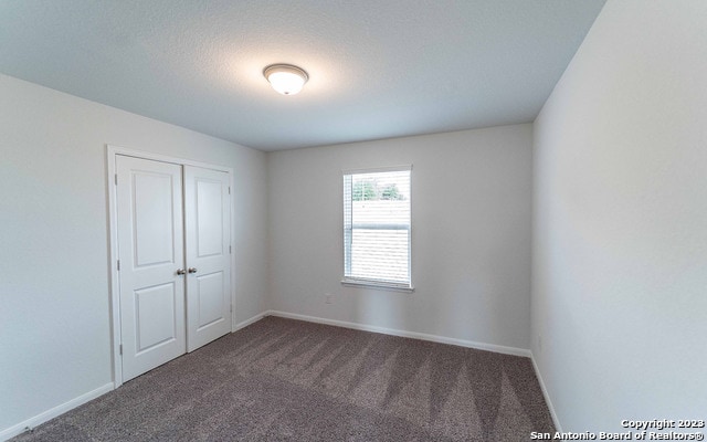 unfurnished bedroom featuring dark carpet and a closet