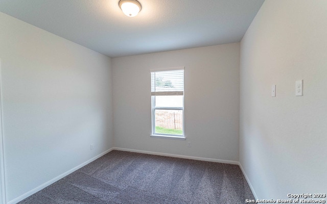 spare room with dark colored carpet