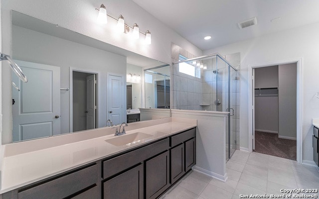 bathroom with walk in shower, tile floors, and vanity