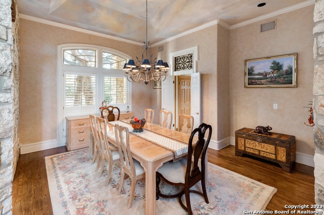 dining space with a chandelier, a raised ceiling, ornamental molding, and dark hardwood / wood-style flooring