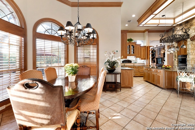 tiled dining room featuring crown molding, a chandelier, and a high ceiling