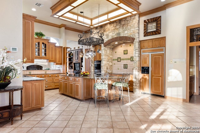 kitchen with a kitchen breakfast bar, a kitchen island, paneled refrigerator, and light tile flooring