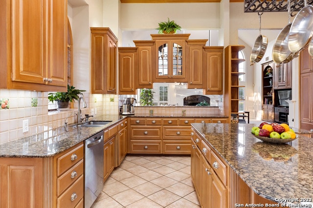 kitchen featuring dark stone countertops, tasteful backsplash, stainless steel dishwasher, and sink