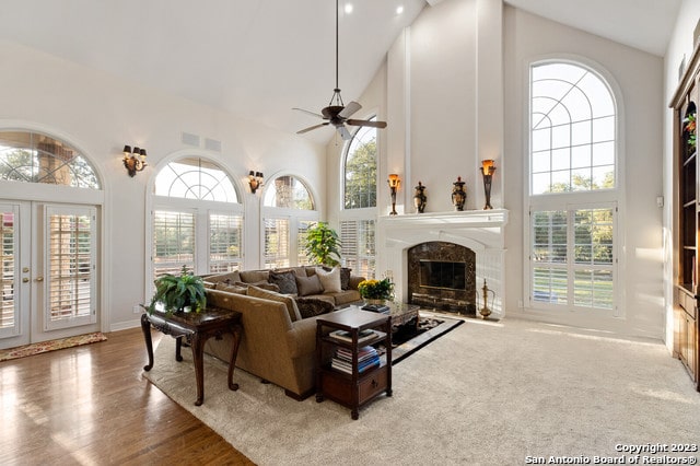 living room with ceiling fan, carpet floors, a fireplace, high vaulted ceiling, and french doors