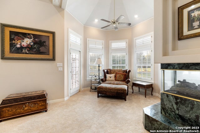 living area featuring light carpet, high vaulted ceiling, ceiling fan, and a wealth of natural light