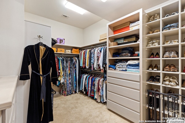 walk in closet featuring light colored carpet