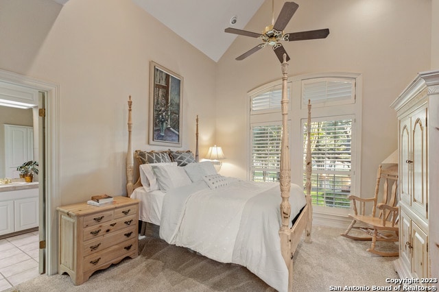 bedroom featuring high vaulted ceiling, ensuite bathroom, light colored carpet, and ceiling fan