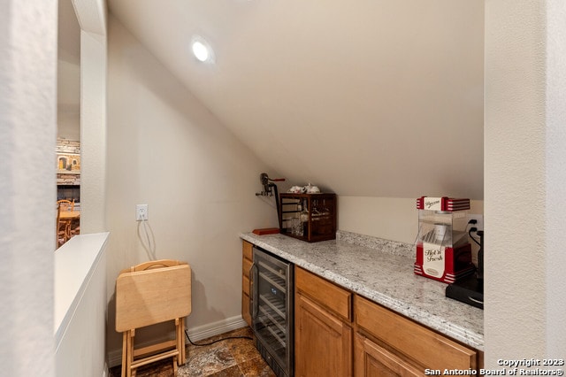 bar featuring light stone counters, tile floors, vaulted ceiling, and wine cooler