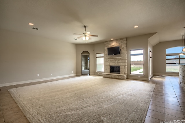 unfurnished living room featuring ceiling fan, a fireplace, and light tile floors