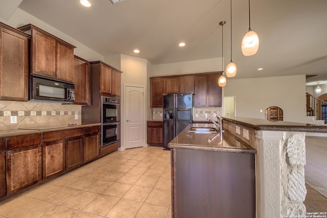 kitchen with hanging light fixtures, backsplash, sink, a kitchen island with sink, and black appliances