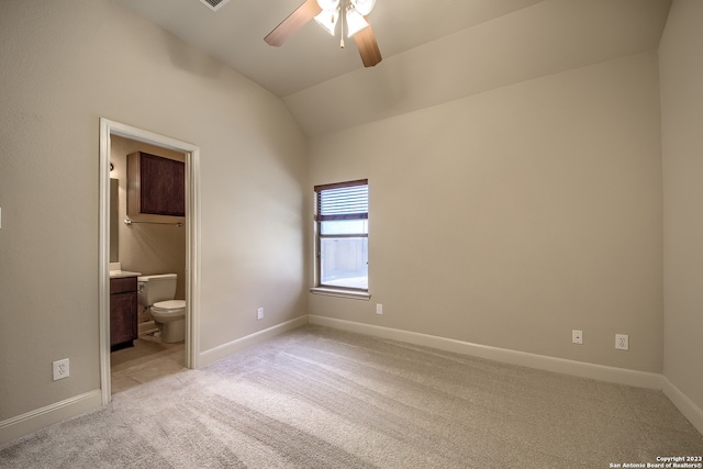 unfurnished bedroom featuring lofted ceiling, ceiling fan, ensuite bath, and light carpet