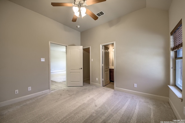 unfurnished bedroom featuring light colored carpet, connected bathroom, vaulted ceiling, and ceiling fan