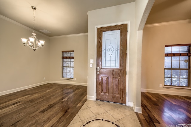 tiled entryway with an inviting chandelier and ornamental molding