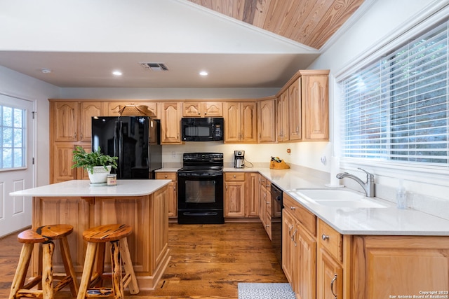 kitchen featuring black appliances, a center island, sink, light hardwood / wood-style flooring, and lofted ceiling