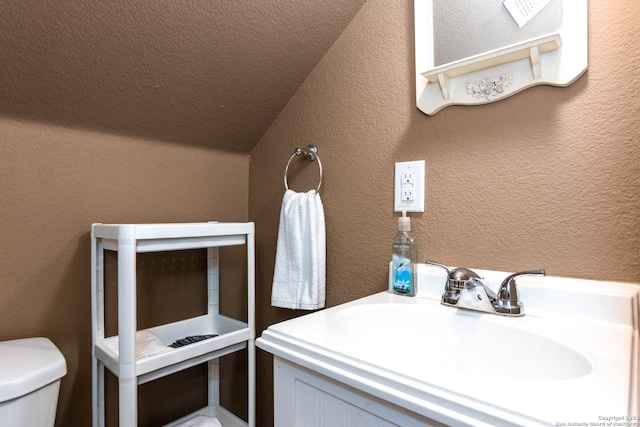 bathroom featuring sink, toilet, and lofted ceiling