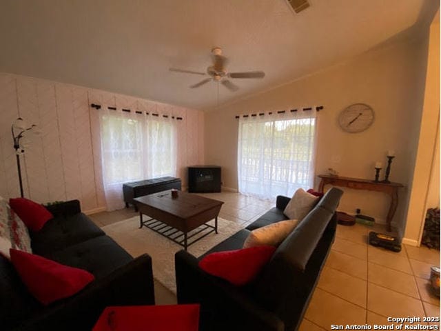 living room with vaulted ceiling, ceiling fan, and light tile floors