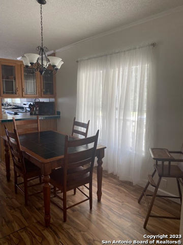 dining room with a textured ceiling, a chandelier, hardwood / wood-style flooring, and crown molding