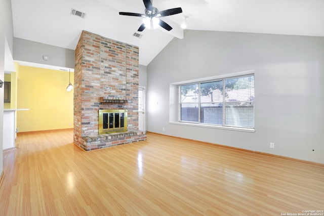 unfurnished living room featuring ceiling fan, brick wall, high vaulted ceiling, light hardwood / wood-style flooring, and a brick fireplace