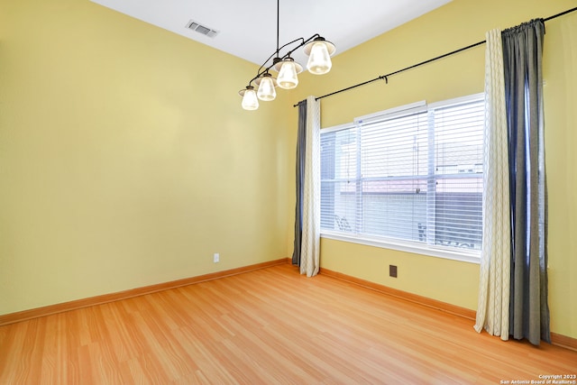 empty room with a notable chandelier and light hardwood / wood-style flooring