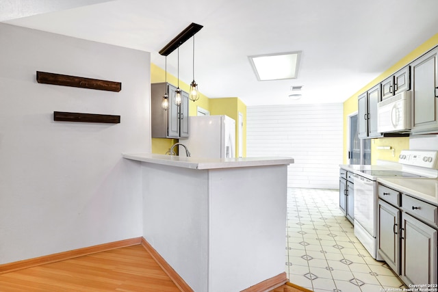 kitchen with light tile floors, kitchen peninsula, gray cabinetry, white appliances, and hanging light fixtures