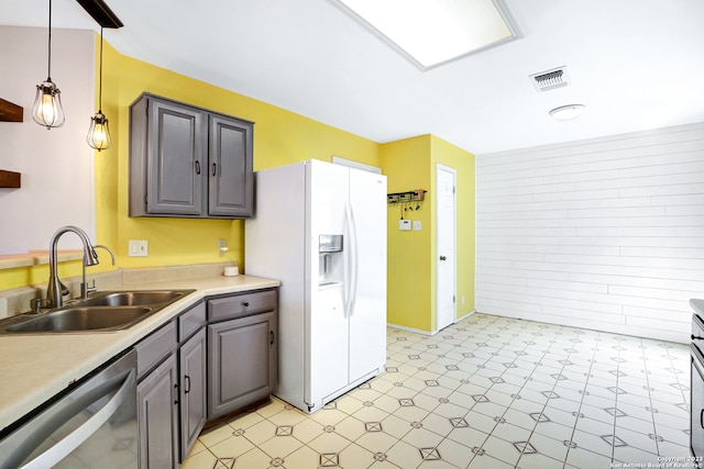 kitchen with sink, light tile floors, hanging light fixtures, stainless steel dishwasher, and white fridge with ice dispenser