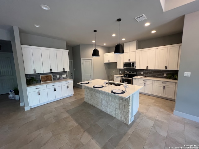 kitchen featuring white cabinets, appliances with stainless steel finishes, and an island with sink