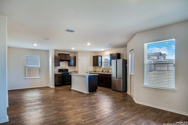 kitchen featuring a kitchen island, stainless steel refrigerator, dark hardwood / wood-style flooring, and black stove