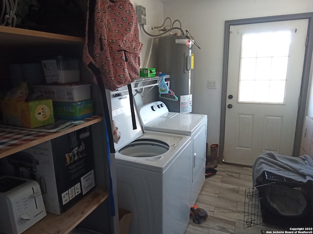 clothes washing area featuring water heater, light hardwood / wood-style floors, and washer and dryer