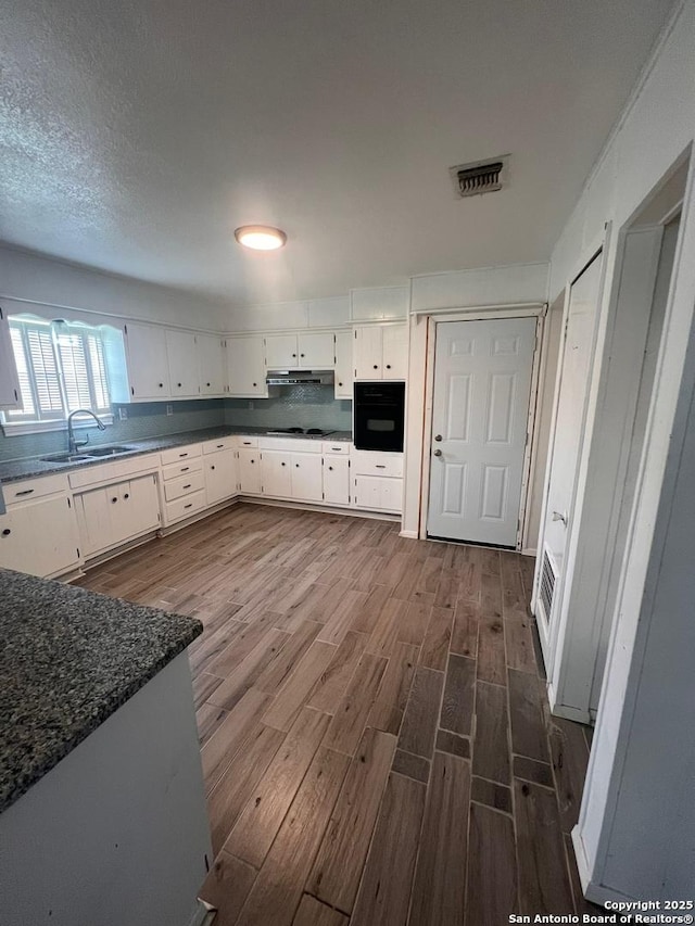 kitchen featuring sink, dark wood-type flooring, white cabinetry, black appliances, and decorative backsplash